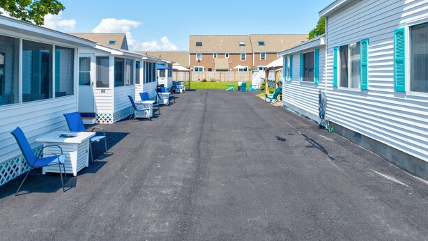 A row of mobile homes with outdoor seating areas and a paved driveway. - Seashell Cottages/JK Rentals - Cottage 1, 2 full beds, 1 twin (Old Orchard Beach)