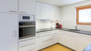 A kitchen with white cabinets, a double oven, a sink, and a window. - Chalet Abendrot apARTments by Interhome (Grindelwald)