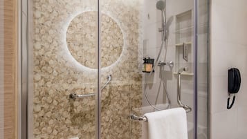 Una ducha moderna con puerta de cristal, un lavamanos integrado y una toalla colgada en la pared.