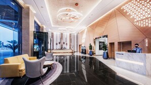 Un moderno vestíbulo de hotel con mostrador de recepción, zona de estar y un amplio ventanal con vistas a la ciudad.