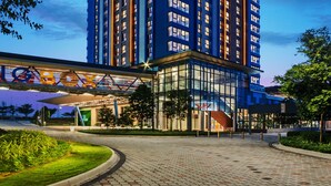 Un hotel moderno con un letrero llamativo, varios pisos y una zona de entrada cubierta.