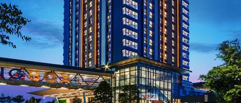 A modern hotel with a prominent sign, multiple floors, and a covered entrance area.