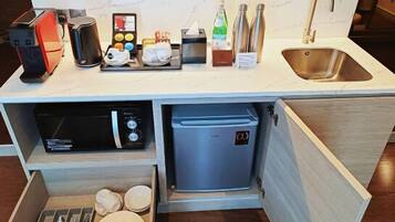 A compact kitchen with a microwave, coffee maker, and a small refrigerator.