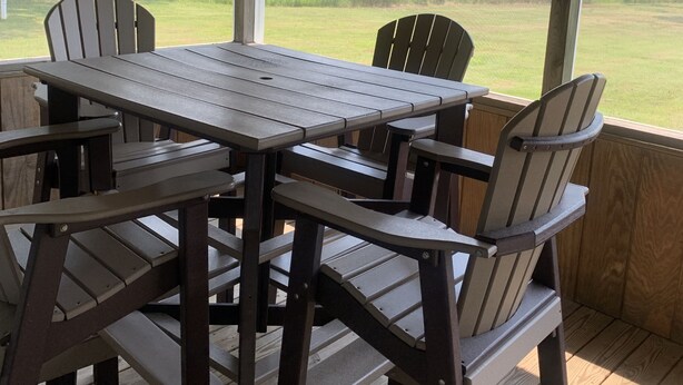 A covered outdoor area with a wooden table and chairs, a ceiling fan, and a view of a grassy field. - Cottage on the Bay (Fishing Creek)
