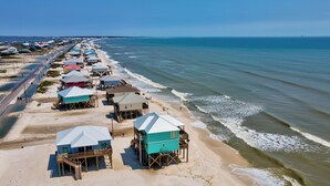 A beachside resort with multiple wooden structures, some elevated on stilts, along a sandy shoreline. - Luxurious Gulf-front home with views, porches, and beach access - Moasis (Dauphin Island)