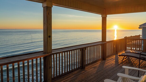 A wooden deck with a railing overlooking the ocean at sunset. - Luxurious Gulf-front home with views, porches, and beach access - Moasis (Dauphin Island)