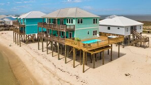 A beachfront property with multiple wooden decked houses, each with a balcony and a pool. - Luxurious Gulf-front home with views, porches, and beach access - Moasis (Dauphin Island)