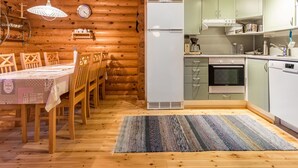 L’intérieur d’un chalet en bois comprend un coin repas, une cuisine et une horloge murale.