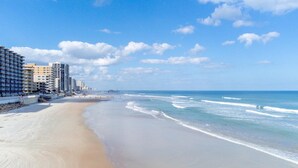 Ein Strand mit einem Steg, Strandhotels und blauem Himmel.