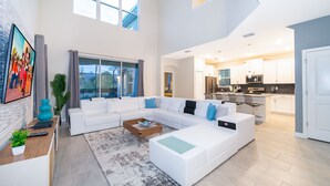 A spacious living area with a sectional sofa, a coffee table, and a large window. - AS2811  Storey Lake Condo 5 bed 5 bath  Free Waterpark (Kissimmee)
