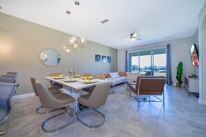 Un comedor moderno con una mesa blanca, sillas marrones y un amplio ventanal con vistas.