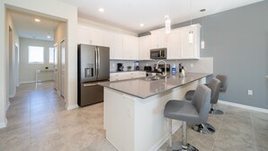 Una cocina moderna con armarios blancos, electrodomésticos de acero inoxidable y una isla grande con taburetes de bar.