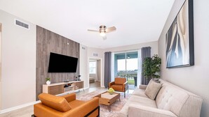 A modern living room with a flat-screen TV, leather sofas, a coffee table, and a ceiling fan. - JC108 Storey Lake, 3Bed&2Bath Free Waterpark (Kissimmee)