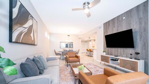 A modern living room with a sofa, armchairs, a coffee table, and a TV mounted on a wooden wall. - JC108 Storey Lake, 3Bed&2Bath Free Waterpark (Kissimmee)