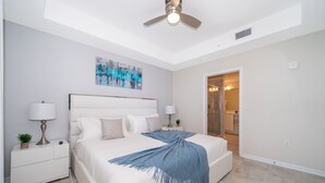 A bedroom with a bed, nightstands, a ceiling fan, and a painting on the wall.