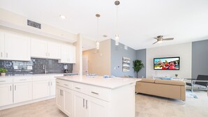 Una cocina moderna con armarios blancos, una isla grande y un televisor de pantalla plana.