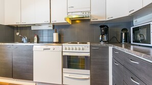 A modern kitchen with white appliances, grey cabinets, and a wooden floor.