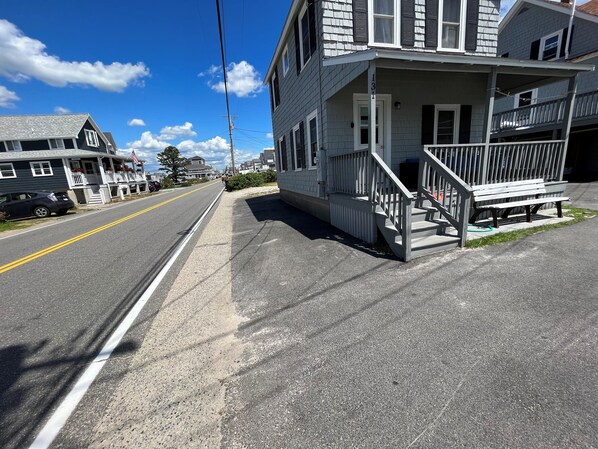A residential street with houses, a sidewalk, and a road with a double yellow line.