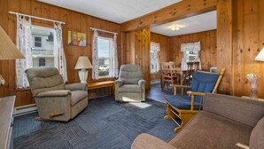 Una habitación acogedora con paredes de madera, alfombra azul y una combinación de sillones y un sofá.