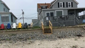 Una playa con una escalera de madera que lleva a una casa con porche.