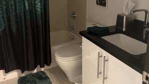 A bathroom with a shower curtain, toilet, sink, and a small rug. - Steps from Gondola, views of Beaver Creek slopes, newly remodeled 2 BR 2BA Condo (Avon)