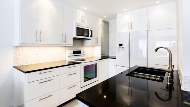 A modern kitchen with white cabinetry, a black countertop, a built-in oven, and a stainless steel sink. - Steps from Gondola, views of Beaver Creek slopes, newly remodeled 2 BR 2BA Condo (Avon)