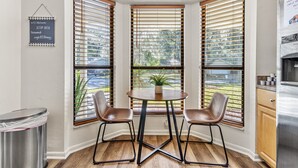 A corner kitchen with two chairs, a small table, and a potted plant. - Stylish Pool Home w/ Grill by GNV's Best Dining! (Gainesville)