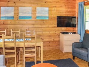 Un interior de madera con una mesa de comedor, sillas, un televisor y un sofá.