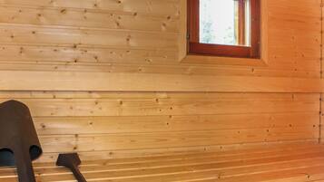 A wooden cabin interior with a window and a pair of skis leaning against the wall.