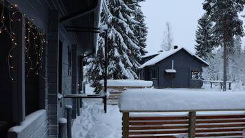 A snow-covered outdoor area with a wooden bench and a building with a dark facade.