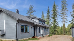 Ein zweigeschossiges Haus mit einem Schotterweg und bewaldeter Umgebung.