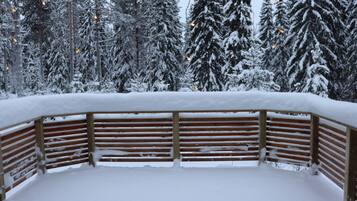A snow-covered wooden bench with a view of snow-laden trees in the background.