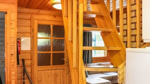 Ein Holzinnenraum mit Treppe, einer Tür mit Fenster und einem weißen Kühlschrank.