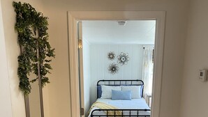 Un dormitorio con cama, suelo de madera y una puerta que da a otra habitación.