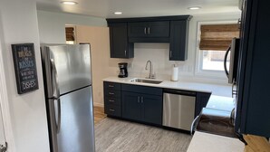 Una cocina moderna con gabinetes oscuros, electrodomésticos de acero inoxidable y lavavajillas.
