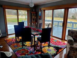 A dining area with a glass table, black chairs, and a colorful rug.