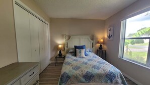 Un dormitorio con cama, mesitas de noche, cómoda y ventana con vistas.