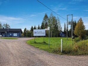 A gravel road leading to a building with a sign indicating 'Paljakan Loma-Asunnot.'