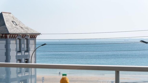 Ein Balkon mit Frühstückstisch und Blick auf einen Strand.