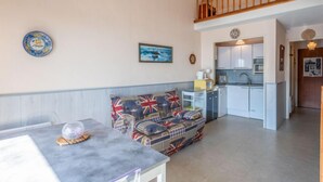 Ein gemütliches Wohnzimmer mit einer Couch, einem Esstisch und einer Küche im Hintergrund.
