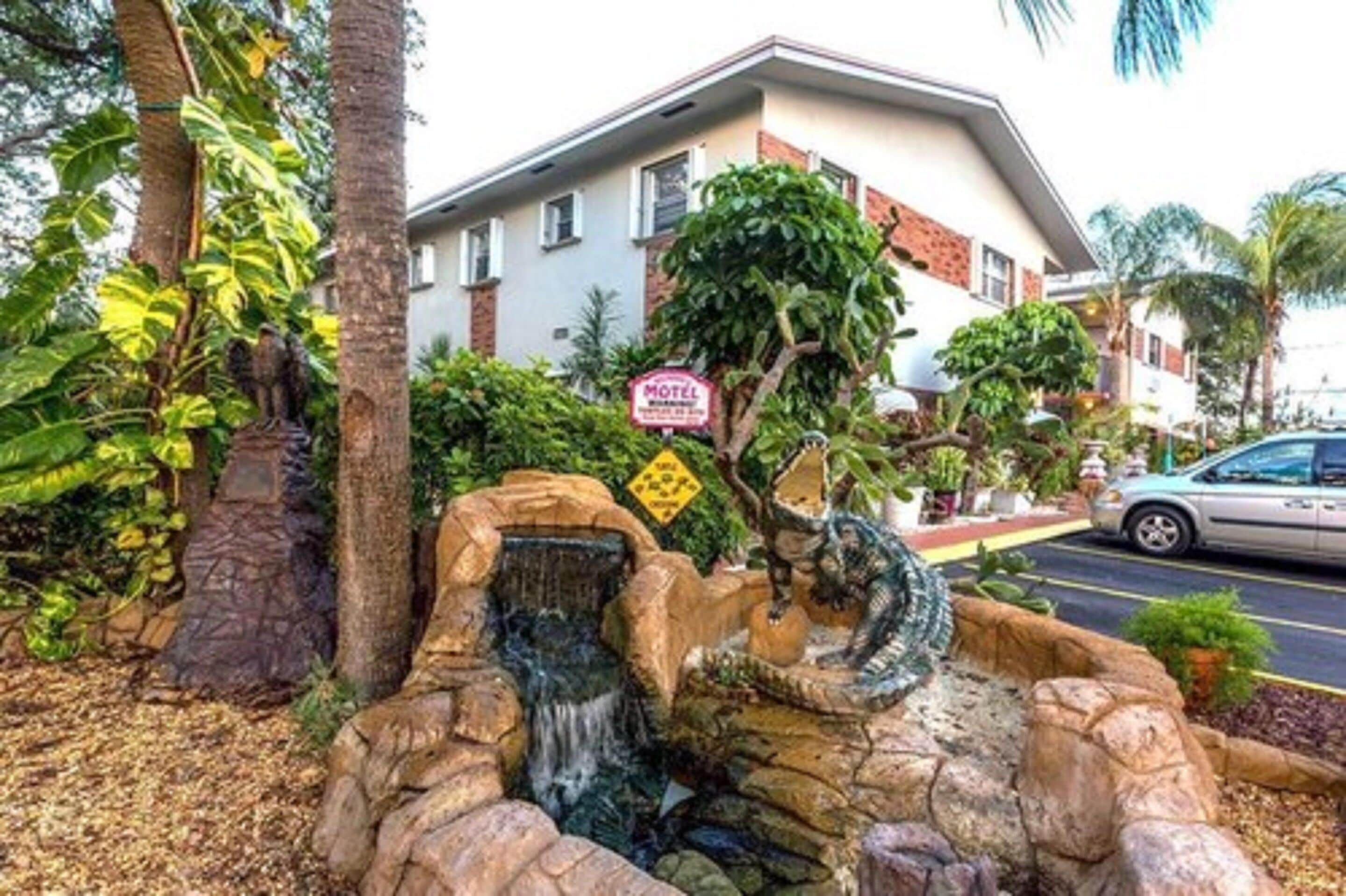 A motel with a waterfall feature, surrounded by tropical vegetation.