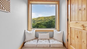 Una habitación acogedora con un banco de madera, un ventanal con vistas a una ladera verde y una puerta de madera.