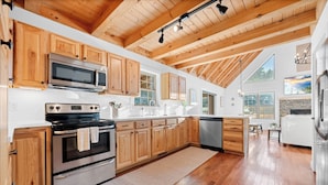 Una cocina amplia con gabinetes de madera, electrodomésticos de acero inoxidable y un ventanal que ofrece luz natural.