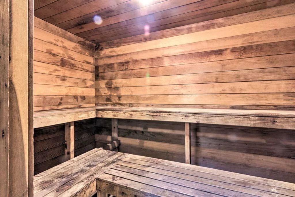 A wooden sauna with benches and a bench in the foreground.