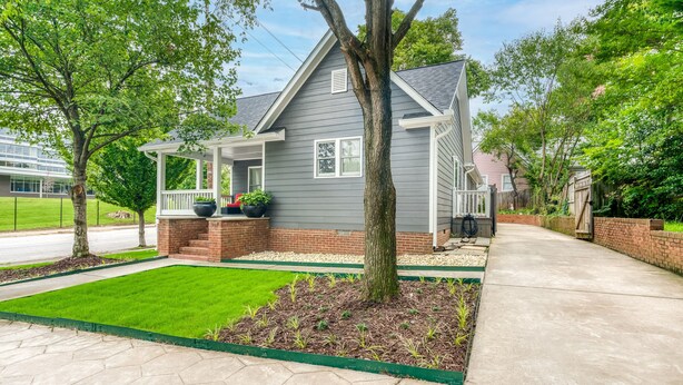 A residential house with a covered porch, a well-maintained lawn, and a brick pathway leading to the entrance. - Heart of Atlanta 4BR Home – 1 Block to Beltline & Krog Street Market (Atlanta)