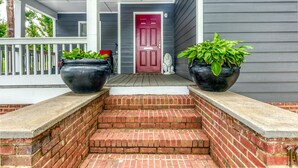 A front porch with a red door, two large potted plants, and a brick staircase leading to the entrance. - Heart of Atlanta 4BR Home – 1 Block to Beltline & Krog Street Market (Atlanta)