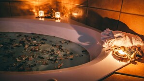 A bathtub with water, candles, and bath salts. - The Elowen Suite (Drumheller)