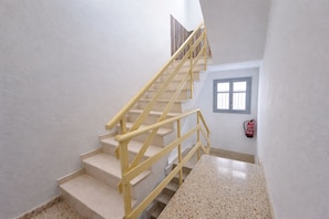 A staircase with yellow handrails leading to a landing.
