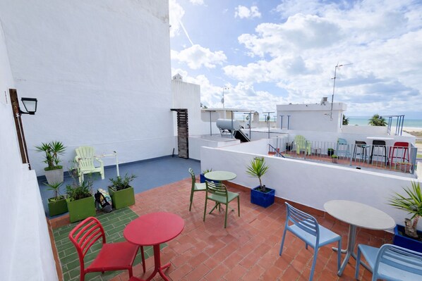 A rooftop terrace with outdoor seating, potted plants, and a view of the ocean. - Cañaveral Playa Conil II Room - right on the beach (Conil de la Frontera)