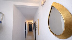 A hallway with white walls, a round mirror with a gold frame, and doors leading to rooms.